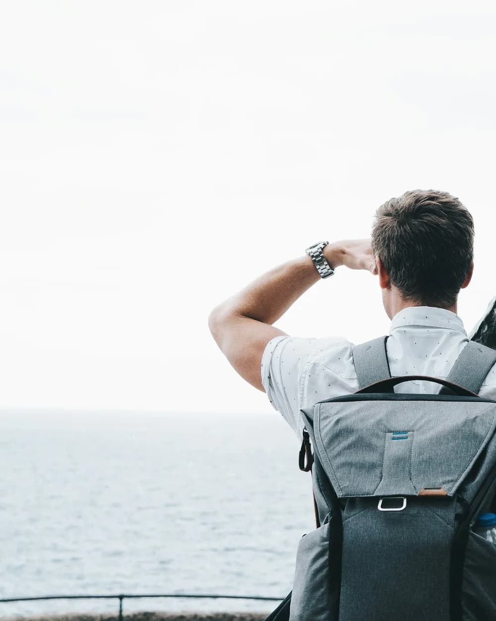 A traveller with a backpack looking out over the sea